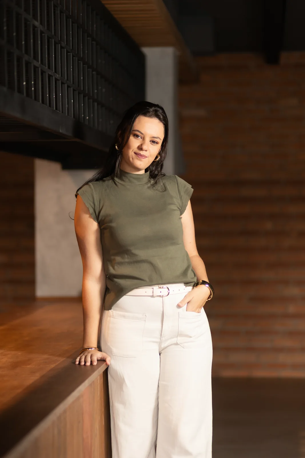 Raquel em pé, em ambiente interno de tons naturais